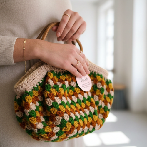 Person holding a colorful crochet handbag with a visible brand tag.