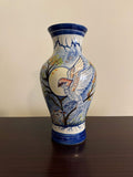 Ceramic vase with a parrot design on a wooden surface