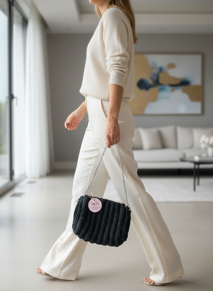 Woman in a white outfit holding a black handbag in a modern living room.