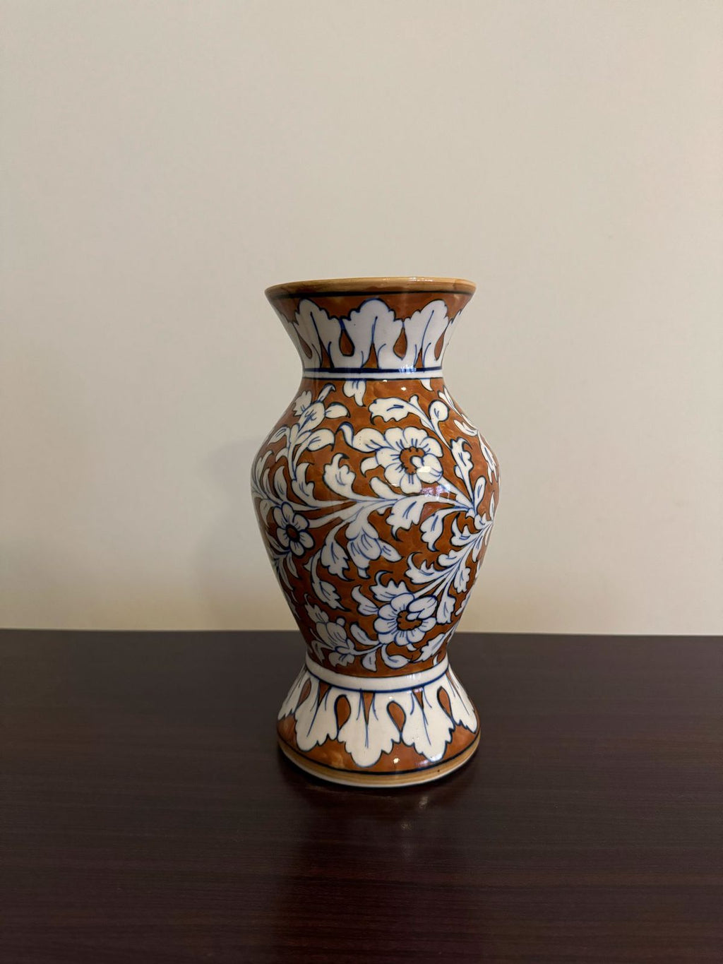 Decorative ceramic vase with brown, white, and blue patterns on a dark surface.