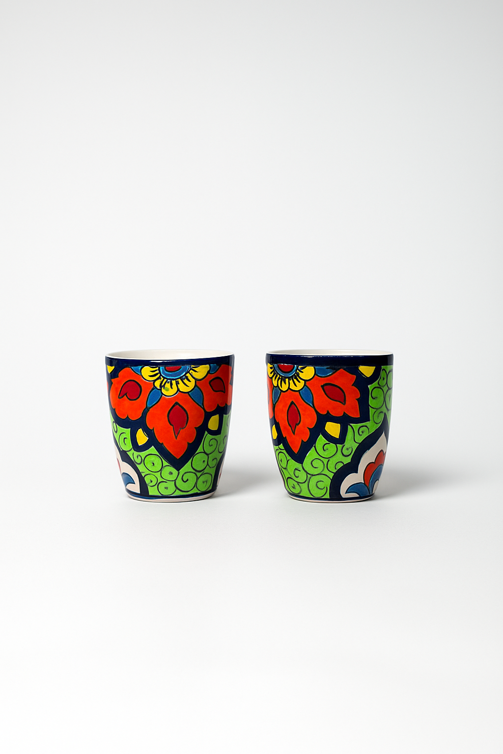 Two colorful ceramic cups with floral patterns on a white background