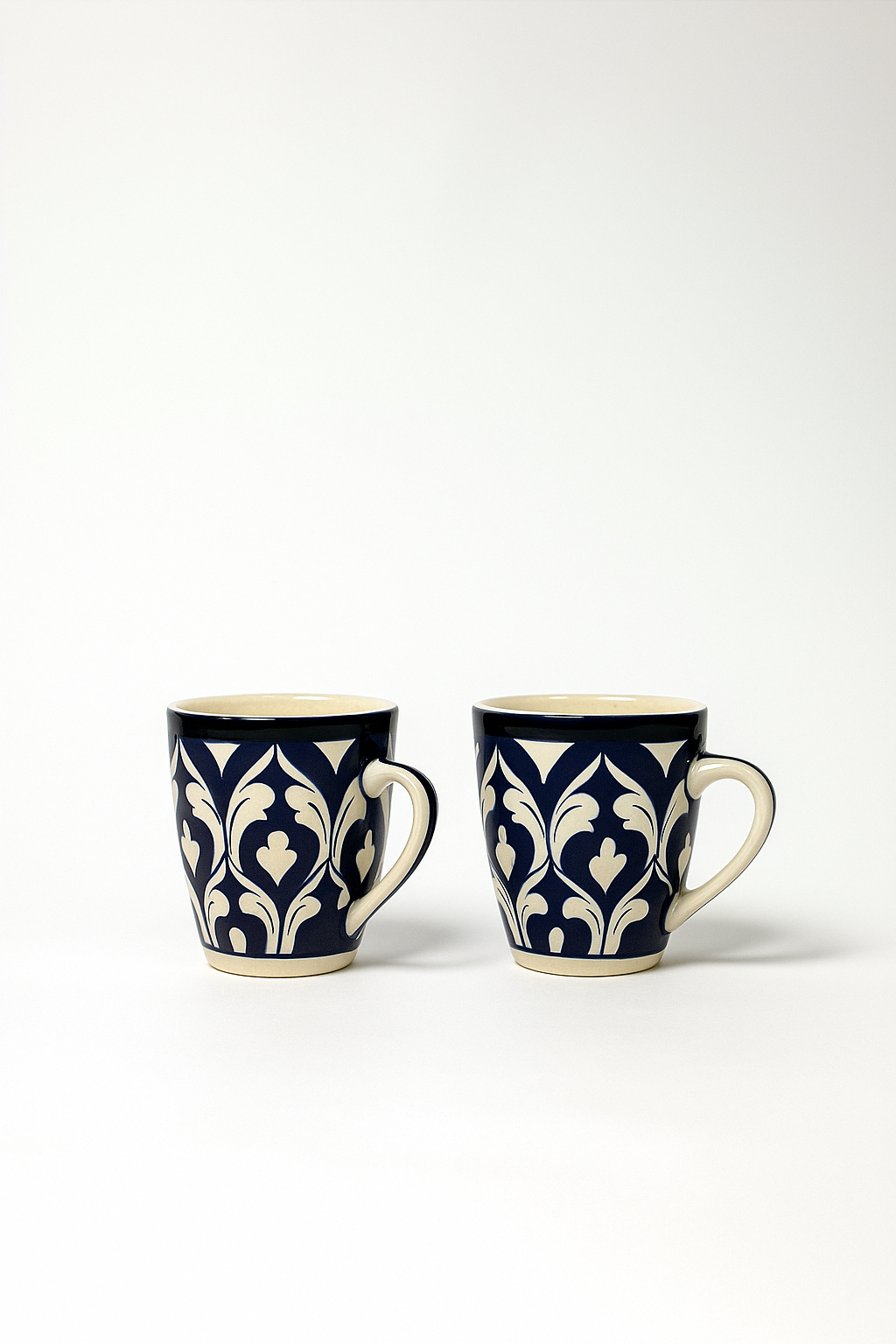 Two blue and white patterned mugs on a white background