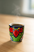 Colorful mug with floral design on a wooden surface with steam rising from it.