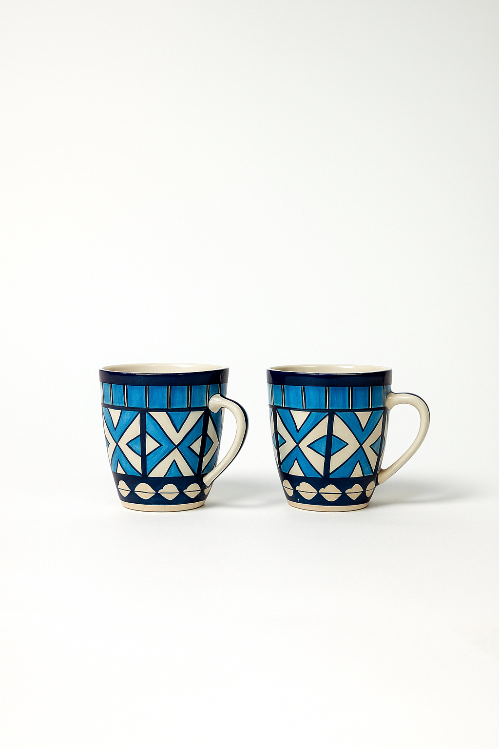 Two ceramic mugs with blue and white geometric patterns on a white background