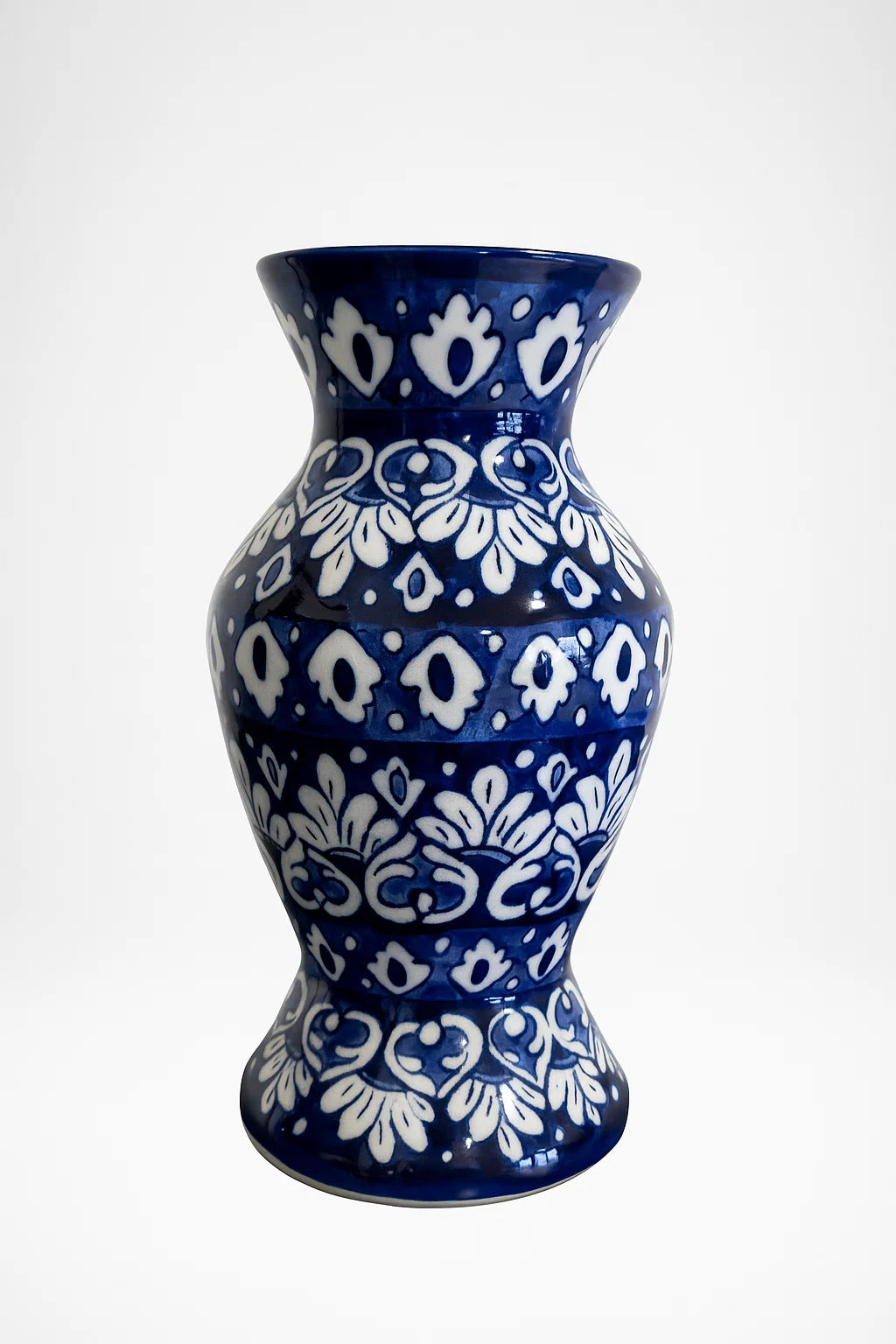 Blue ceramic vase with white floral patterns on a white background